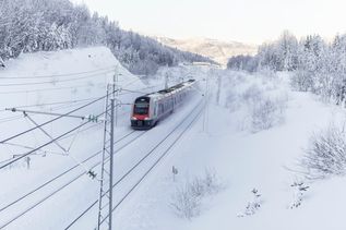 Zug fährt durch eine verschneite Landschaft in Norwegen