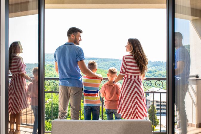 Eine Familie mit zwei Kindern steht Arm in Arm auf einem Balkon 