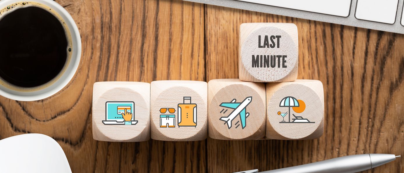 Auf einem Schreibtisch liegen Holzwürfel mit Symbolen drauf in einer Reihe und einem darüberliegenden Würfel, wo "Last Minute" drauf steht