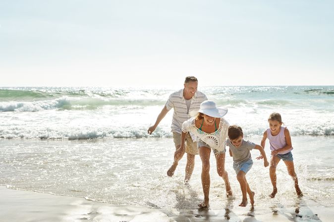 Eine Familie am Strand läuft lachend durch das Wasser