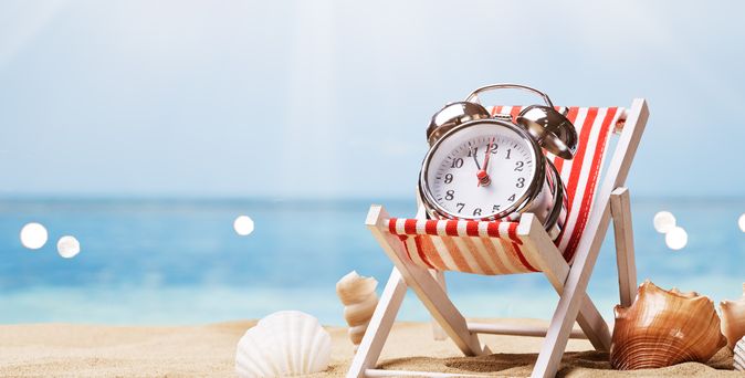 Ein Wecker liegt in einer Liege am Strand