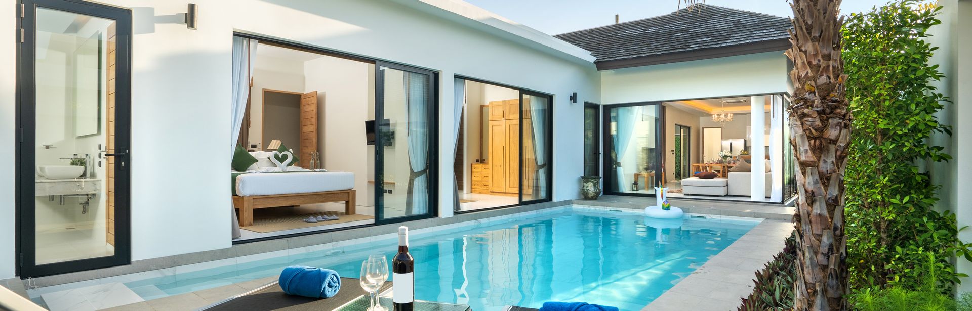 Ein Pool vor einer eleganten Villa mit zwei Liegen und einem Tisch