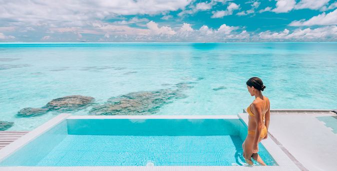 Eine Frau steigt in einen erhöht über dem Strand gelegen Pool