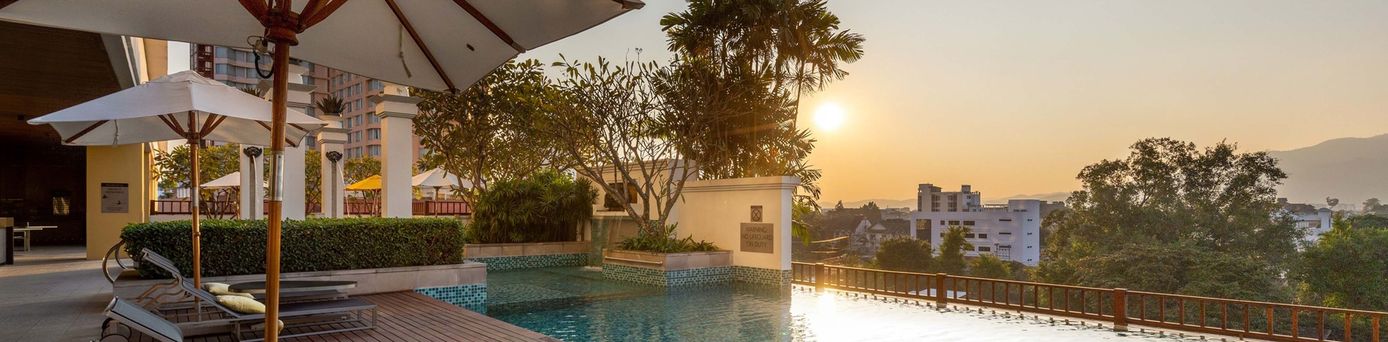Pool mit zwei Liegen bei Sonnenuntergang