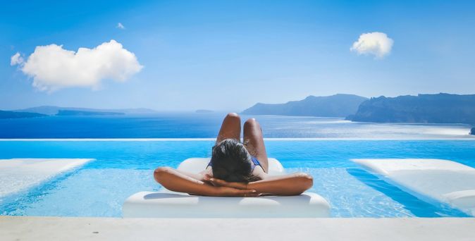 Eine Frau liegt auf einer Liege im Pool mit Blick auf das Meer