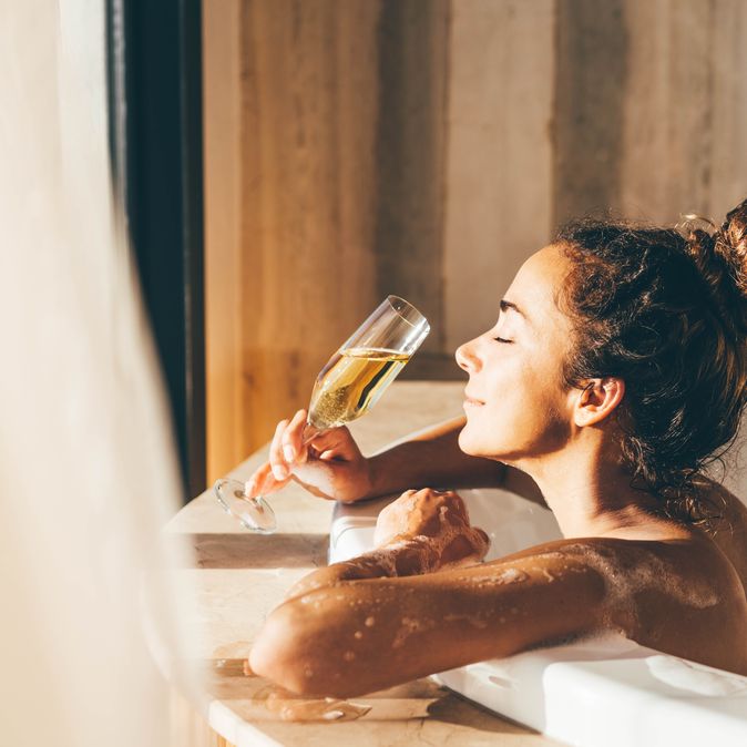 Eine Frau lehnt am Rand eines Whirlpools und genießt ein Glas Sekt