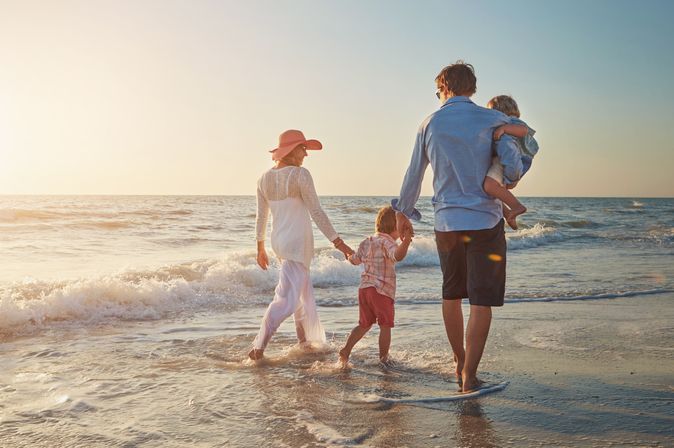 Familie, die einen Strandspaziergang beim Sonnenuntergang macht