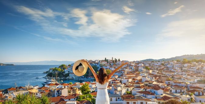 Eine glückliche Touristin genießt den schönen Sonnenuntergang im Sommer mit Blick auf die Stadt 