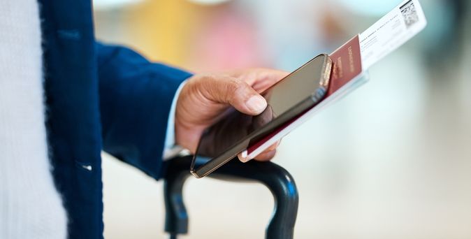 Eine Person hält einen Reisepass und Flugtickets in der Hand