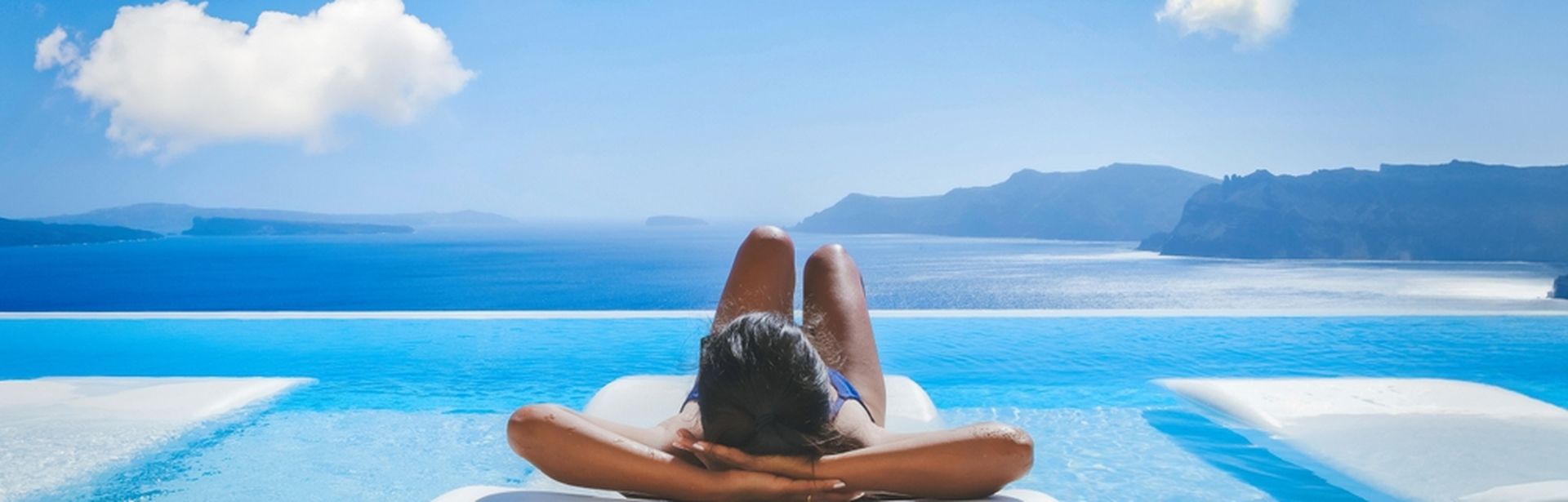 Eine Frau liegt auf einer Liege im Pool mit Blick auf das Meer