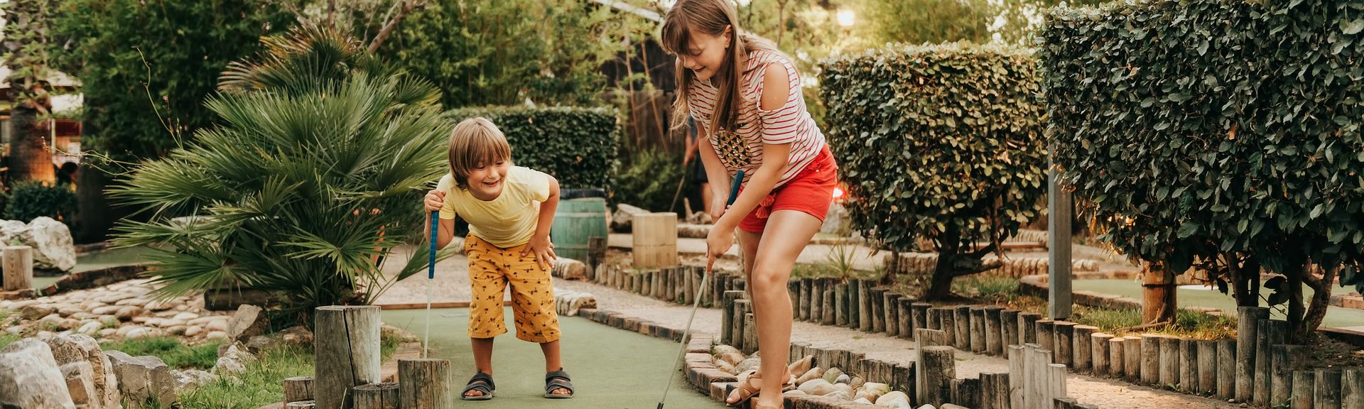 Zwei Kinder spielen Minigolf in einem Clubhotel