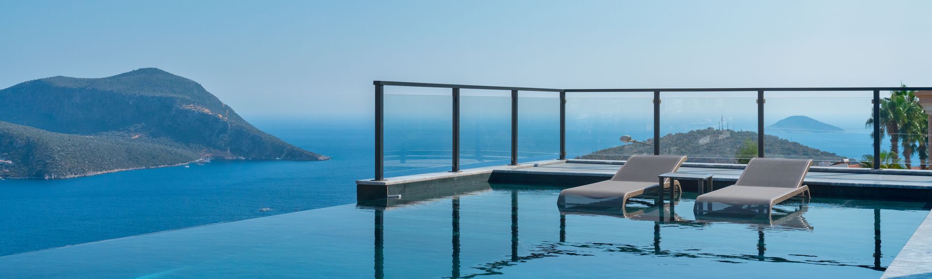 Infinity Pool mit zwei Liegen und dem Meer im Hintergrund