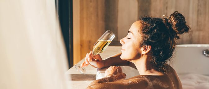 Eine Frau lehnt am Rand eines Whirlpools und genießt ein Glas Sekt