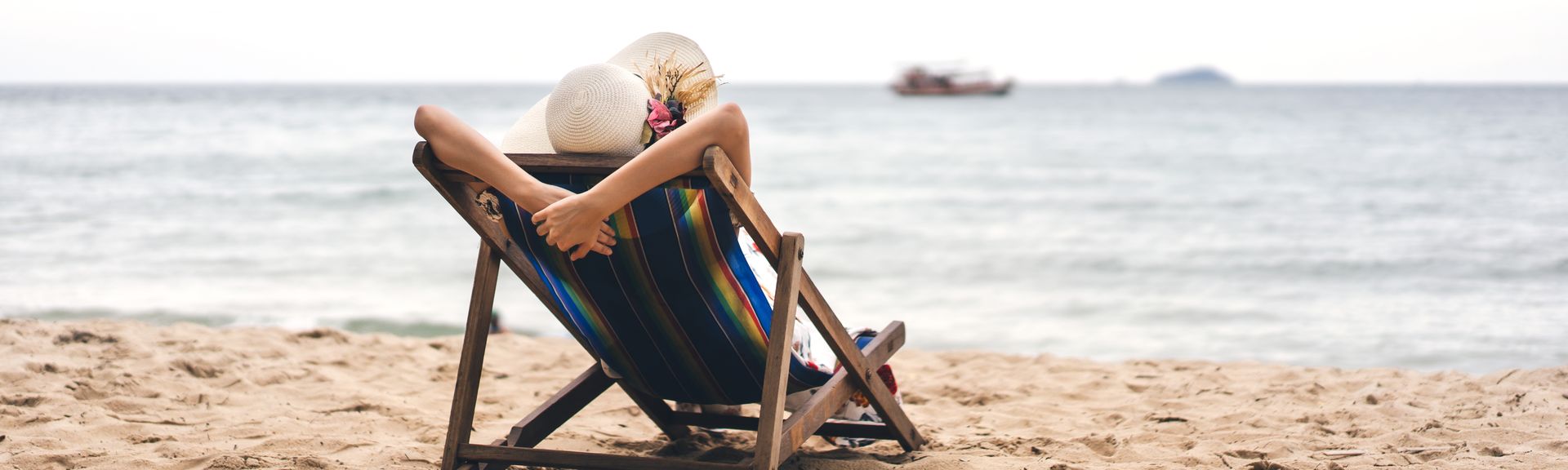 Person am Strand auf einer Liege schaut auf das Meer