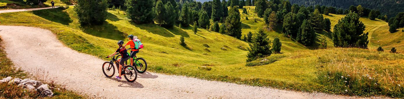 Zwei Personen fahren bei gutem Wetter Fahrrad durch eine Berglandschaft