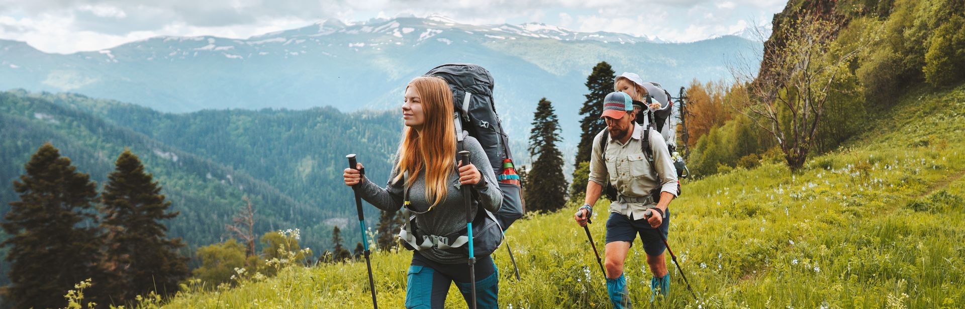 Zwei Personen wandern mit Nordic Walking Stöckern durch eine Wiese
