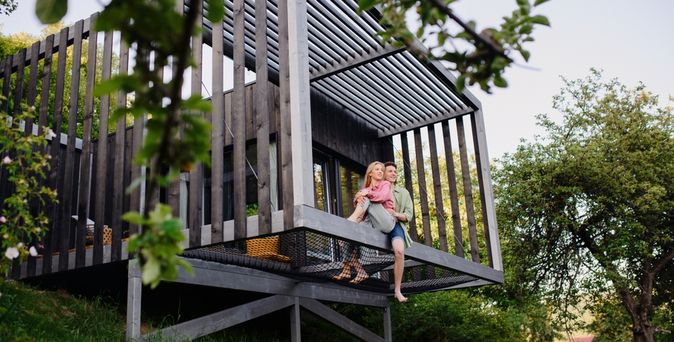 Eine Frau und ein Mann sitzen arm in Arm am Rand eines Hauses am Rand eines Hügels