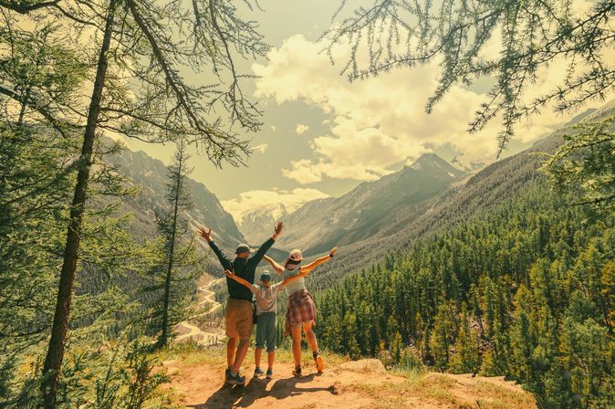 Eltern und Kind schauen beim Wandern gemeinsam auf eine Berglandschaft 