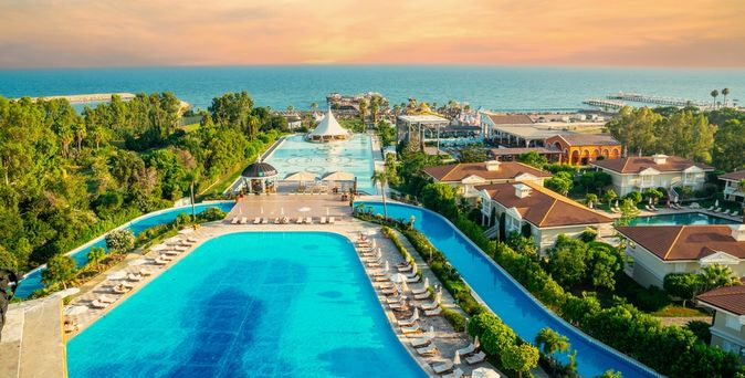 Zwei große Pools umgeben von Bäumen und mit Blick auf das Meer