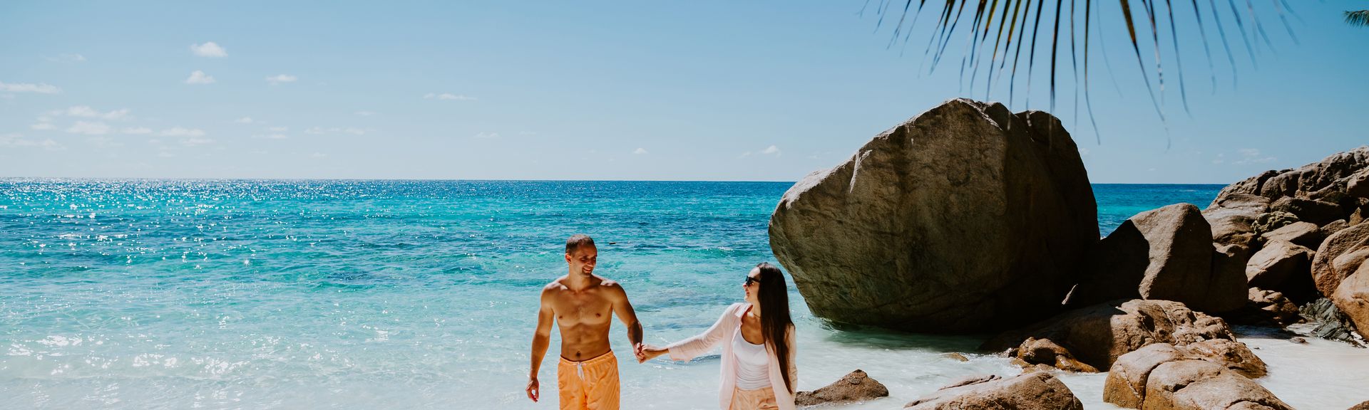Paar läuft händchen haltend am Strand entlang