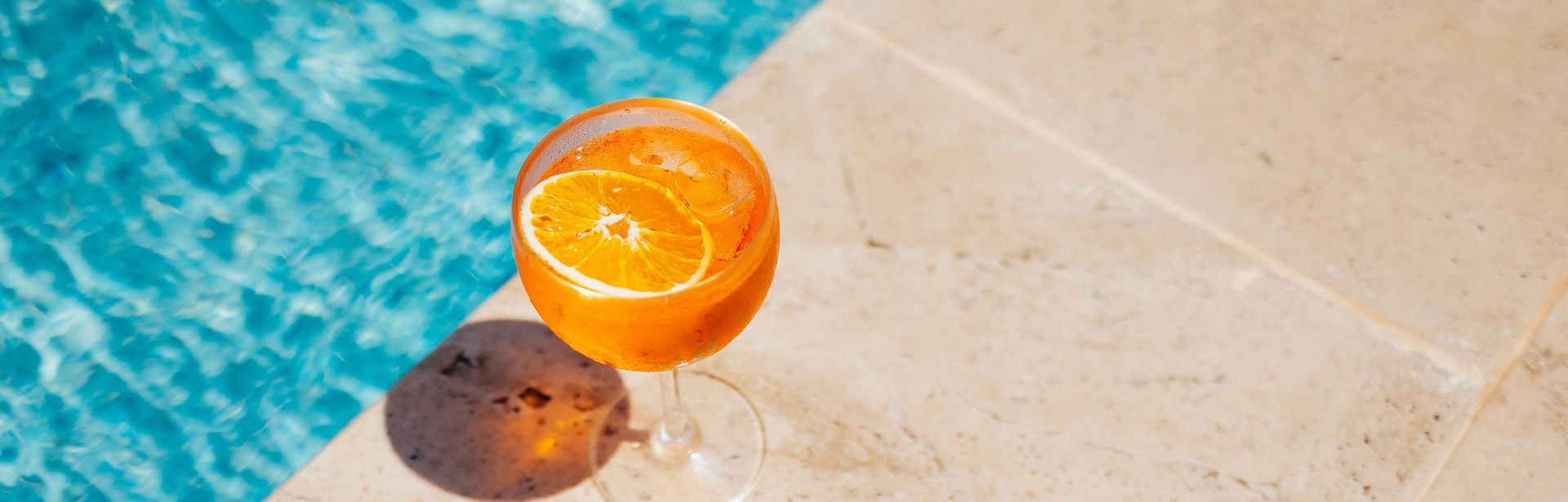 Ein Oranges Getränk steht am Rand eines Pools