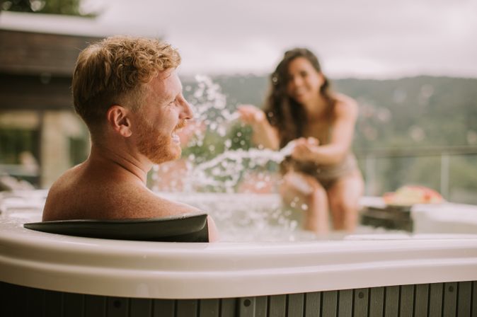 Zwei Personen im Whirlpool, die Frau macht den lachenden Mann nass