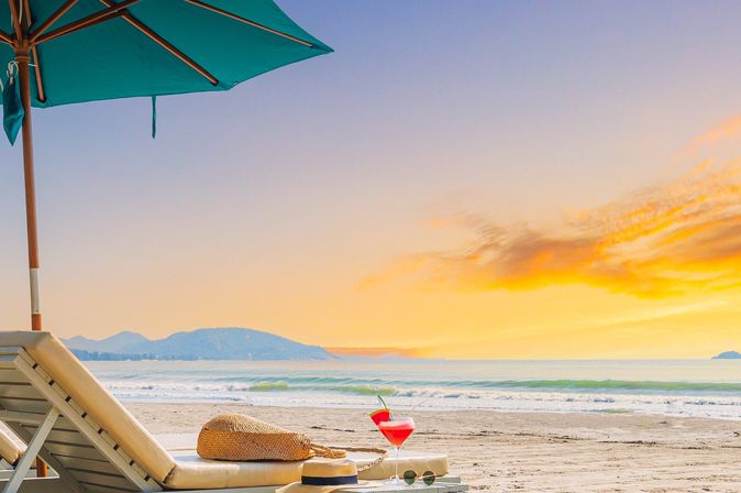 Zwei Liegen mit Sonnenschirm stehen am Strand