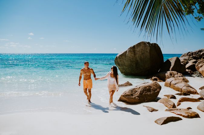 Paar läuft händchenhaltend am Strand entlang