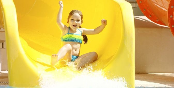 Mädchen rutscht glücklich auf einer Wasserrutsche