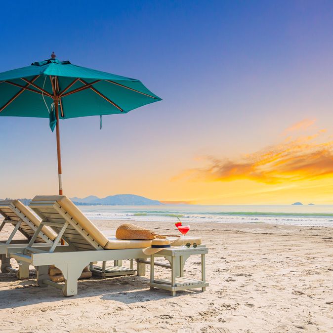 Zwei Liegen mit Sonnenschirm stehen am Strand