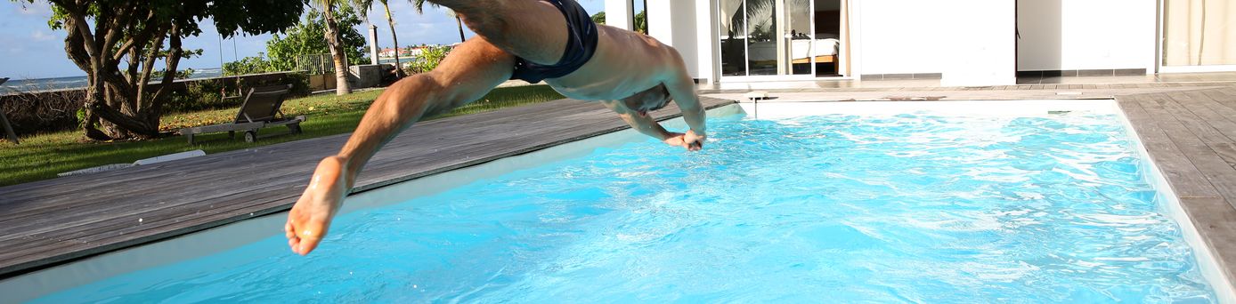 Ein Mann springt Kopfüber in einen großen privaten Pool
