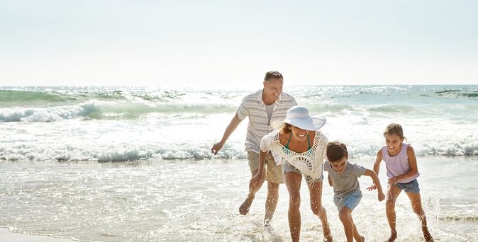 Eine Familie am Strand läuft lachend durch das Wasser