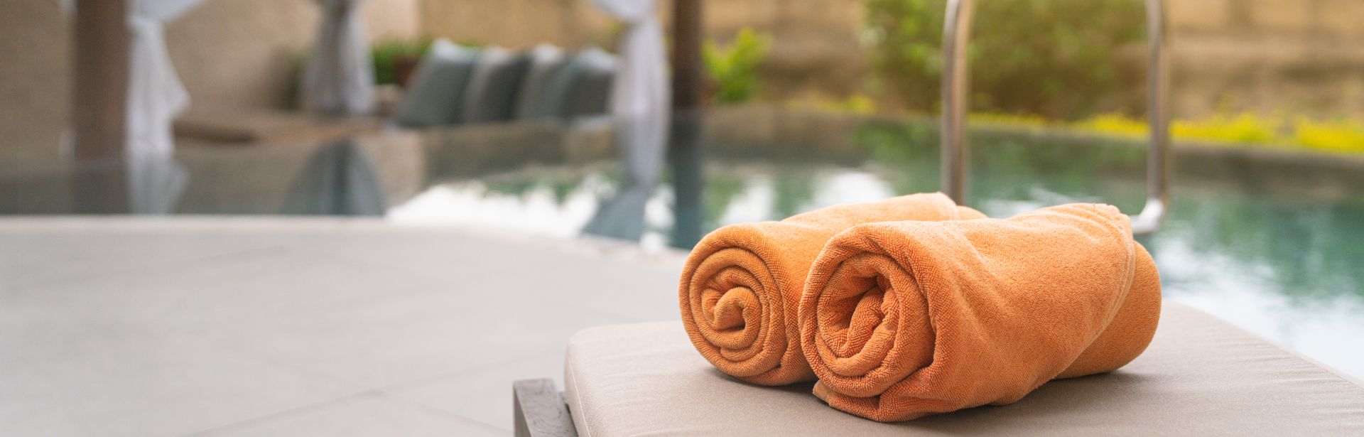 Aufgerollte Handtücher auf einer Liege am Pool