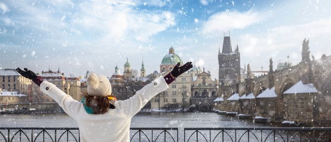 Eine Frau steht vor einem Zaun an einem Fluss, der durch eine Stadt fließt, während es schneit