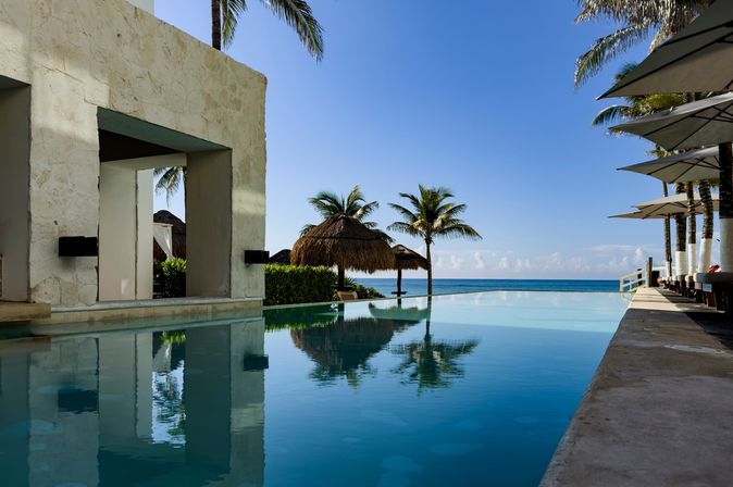 Ein Pool umgeben von Palmen und mit Blick auf das Meer
