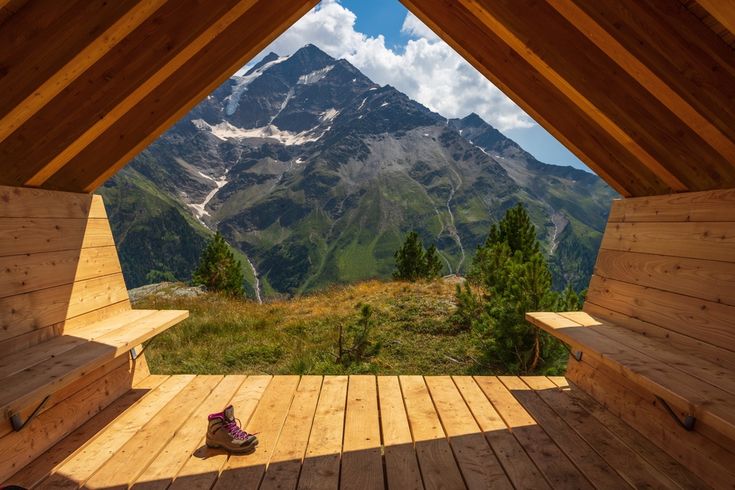 Aus einer Holzhütte mit zwei Bänken schaut man auf eine beeindruckende Berglandschaft