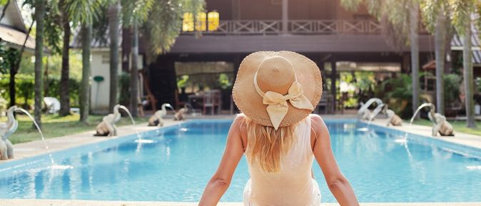 Eine Frau sitzt am Pool und sonnt sich 