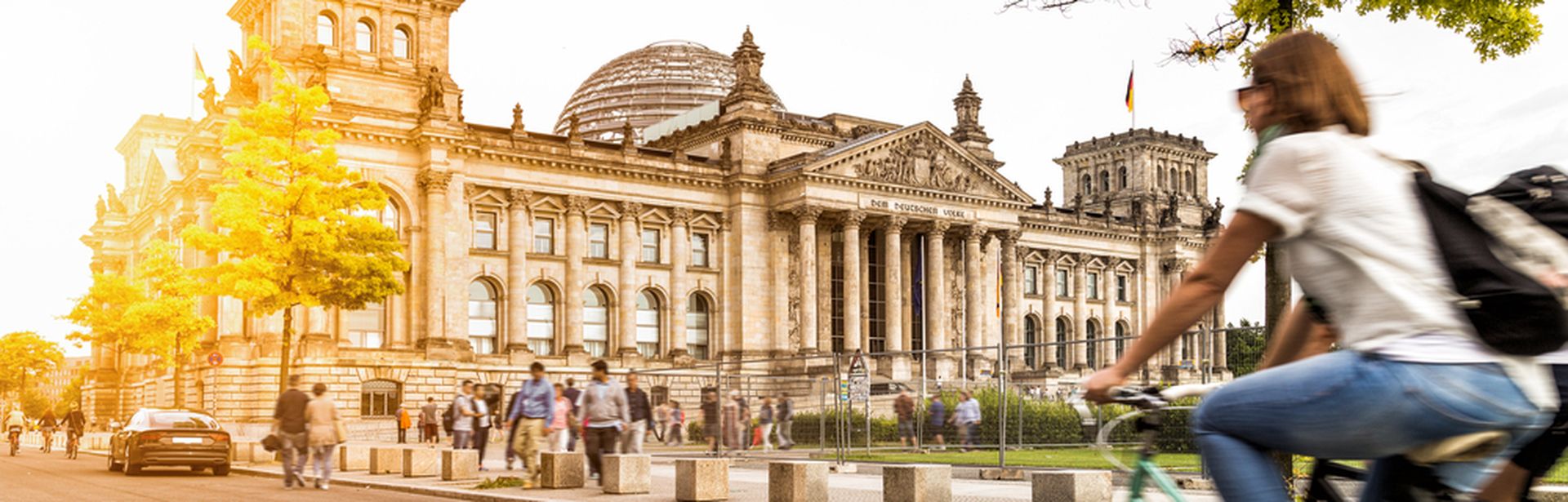 Eine Frau fährt bei Sonnenschein auf dem Fahrrad am Berliner Bundestag vorbei