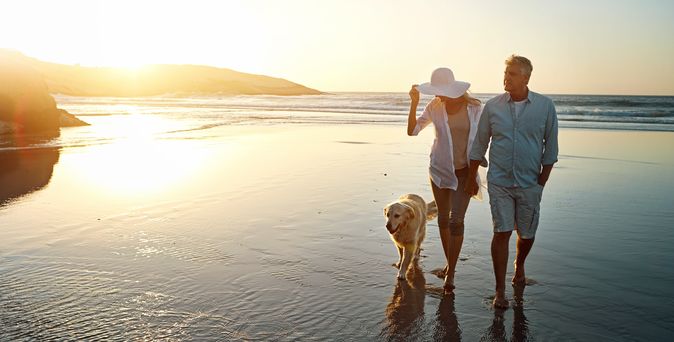 Ehepaar macht mit Ihrem Hund einen Spaziergang am Strand