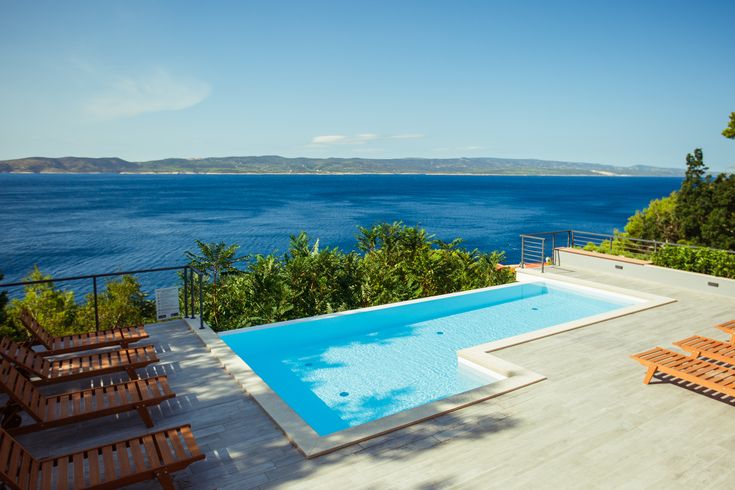 Ein Privatpool über dem Meer, um ihn herum einige Holzliegen und Bäume