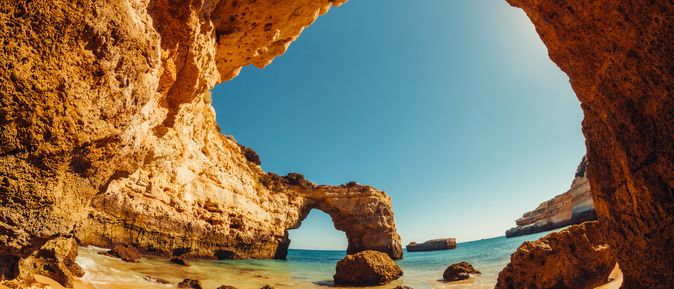 Blick auf einen Strand unter einem Felsdach.