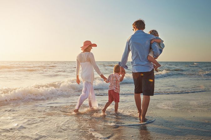 Familie, die einen Strandspaziergang beim Sonnenuntergang macht