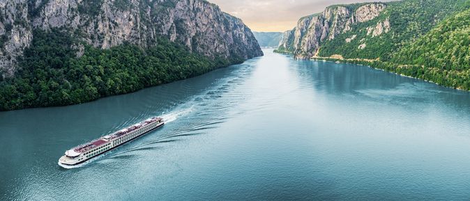 Flusskreuzfahrschiff fährt durch einen Fluss, umgeben von steilen Klippen