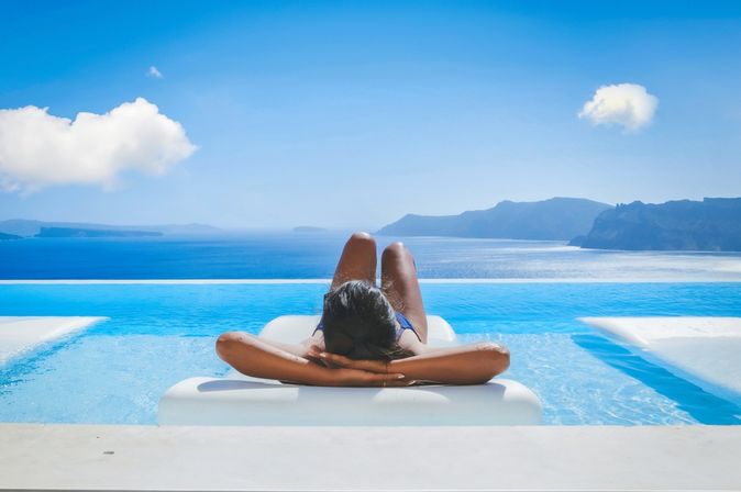 Eine Frau liegt auf einer Liege im Pool mit Blick auf das Meer