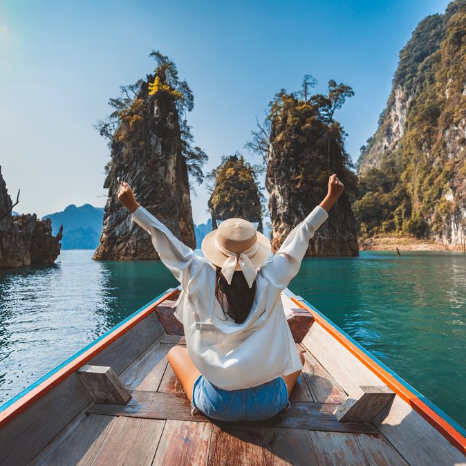Alleinreisende Frau in einem Boot auf dem Wasser in Thailand