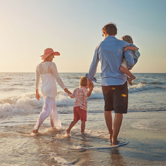 Familie, die einen Strandspaziergang beim Sonnenuntergang macht