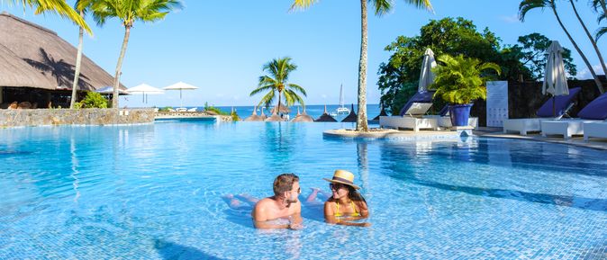 Zwei Personen liegen im Pool umgeben von Palmen