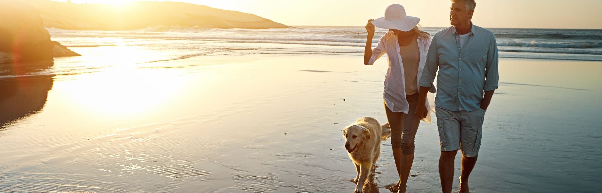 Ehepaar macht mit Ihrem Hund einen Spaziergang am Strand