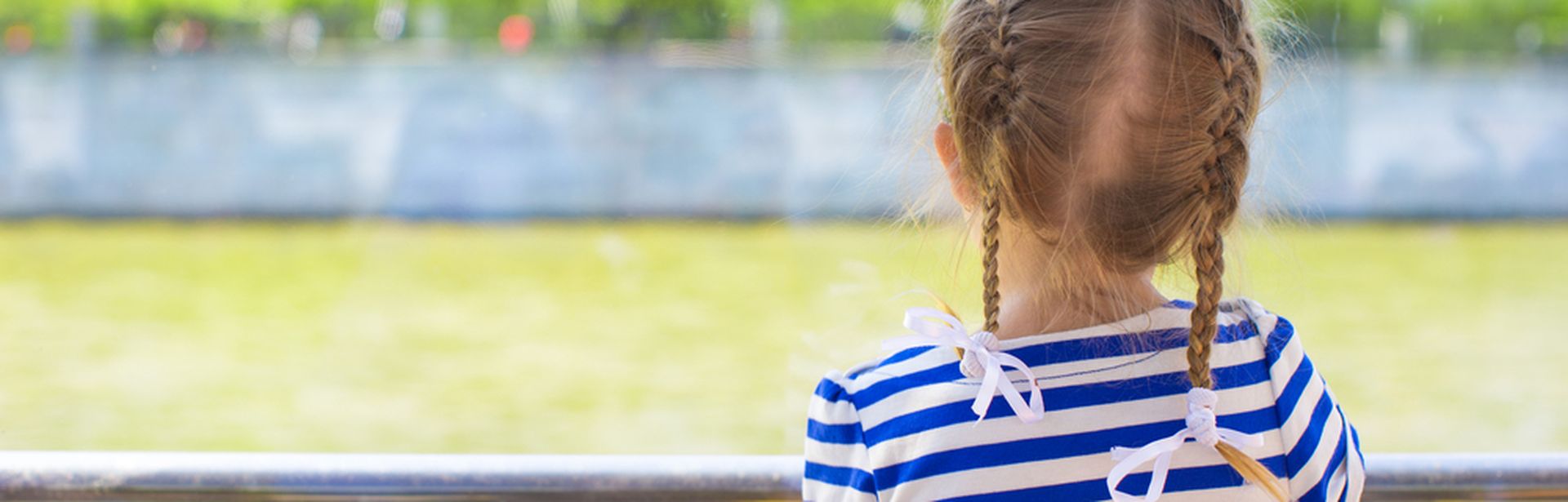 Mädchen mit geflochteten Haaren schaut auf eine grüne Wiese