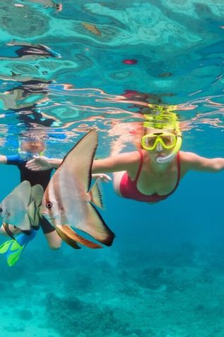 Zwei Kinder tauchen mit Taucherbrille und Schnorchel zwischen Fischen
